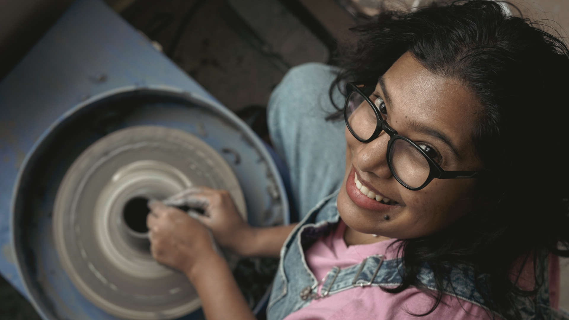 Potter smiling up while hands shape clay